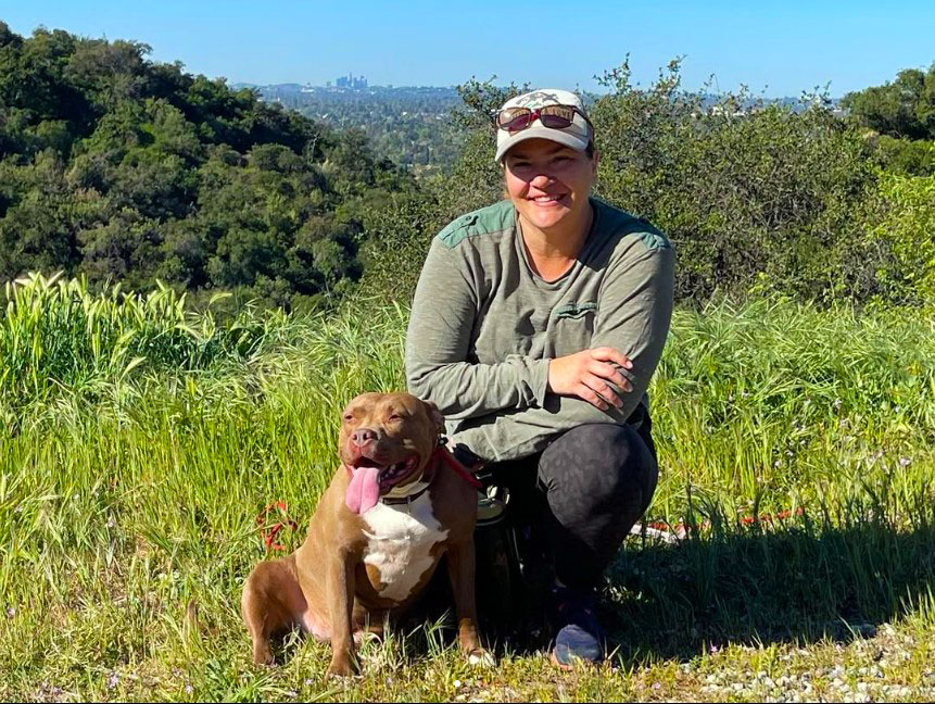 Stephanie-edited Stephanie Aikin with her dog on a grassy hills with the City of Los Angeles behind her.